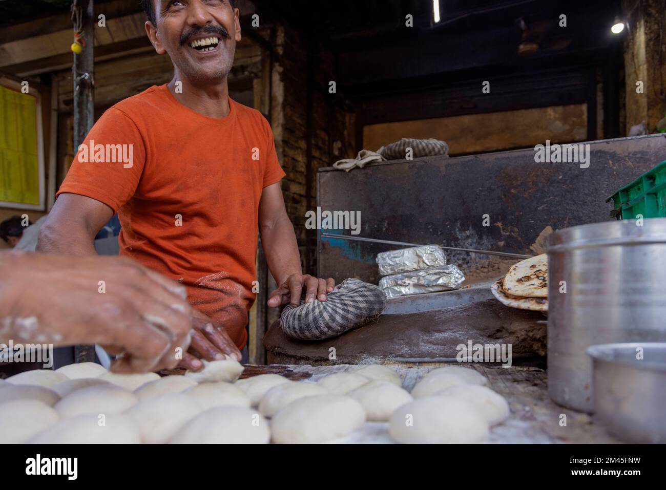Cuoco di un locale ristorante sulla strada o un dhaba, facendo il pane o un roti, in un forno a legna di argilla o un tandoor Foto Stock
