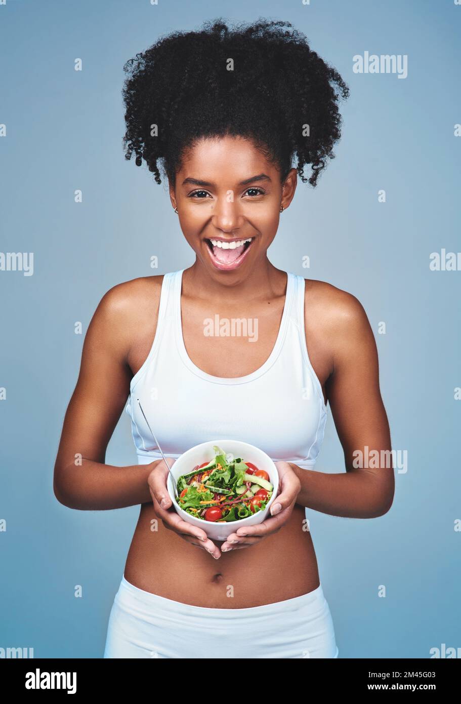 Più sano si mangia, più sano sarà il giovane. Studio shot di una giovane donna attraente che mangia insalata su uno sfondo grigio. Foto Stock