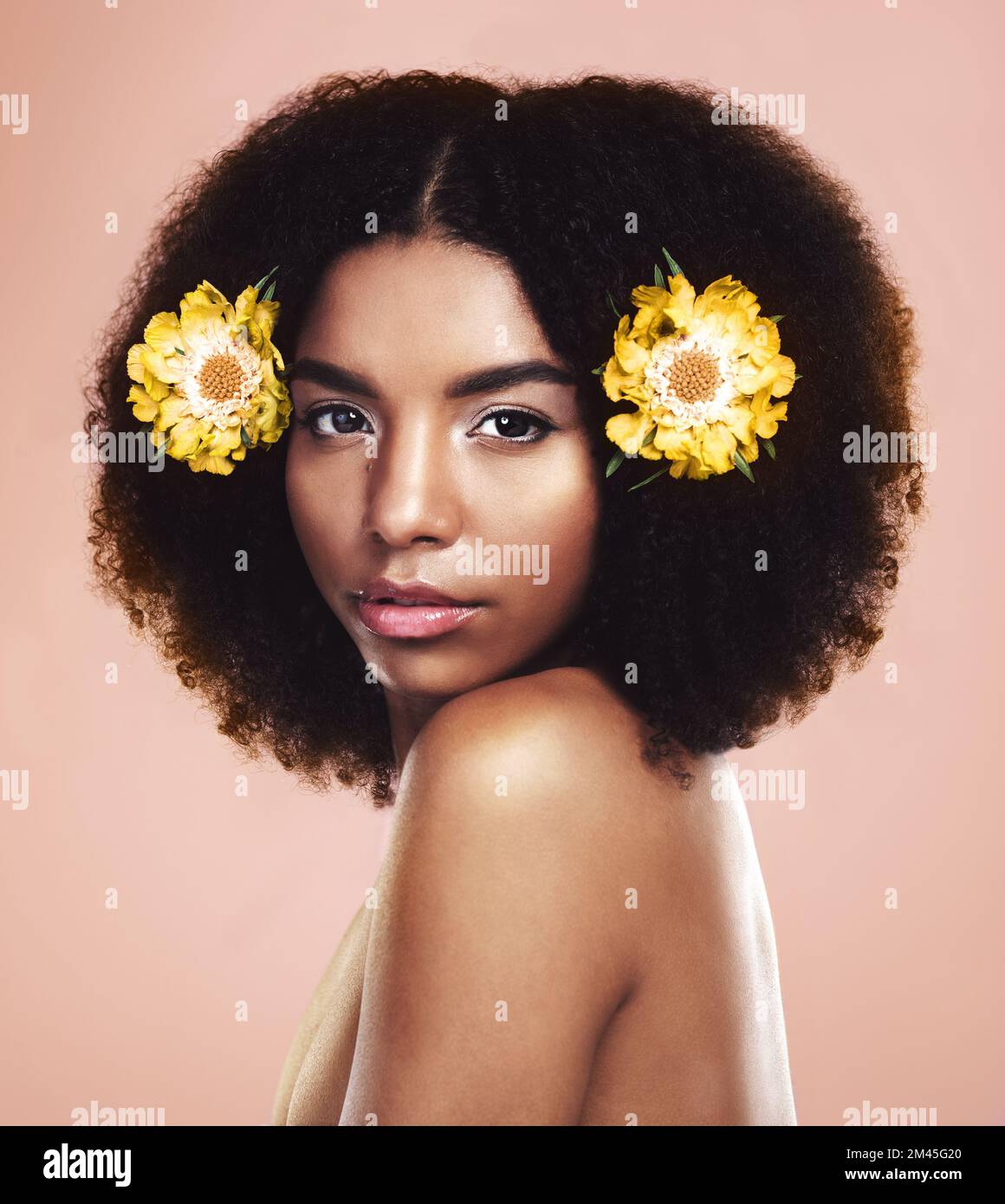 Bello come un fiore. Studio shot di una bella giovane donna in posa con fiori nei suoi capelli. Foto Stock