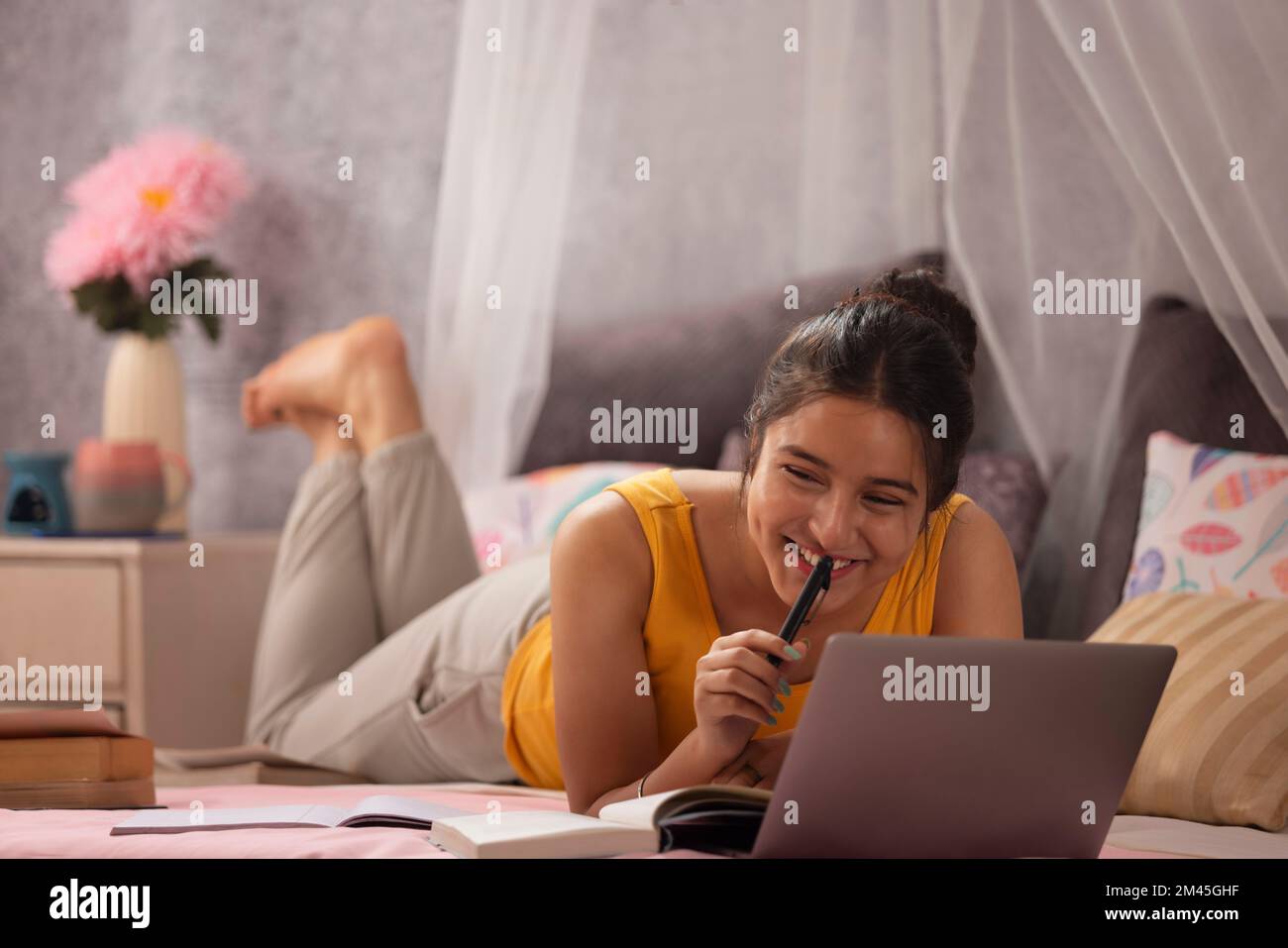 Ragazza adolescente sdraiata a letto e studia con il laptop Foto Stock
