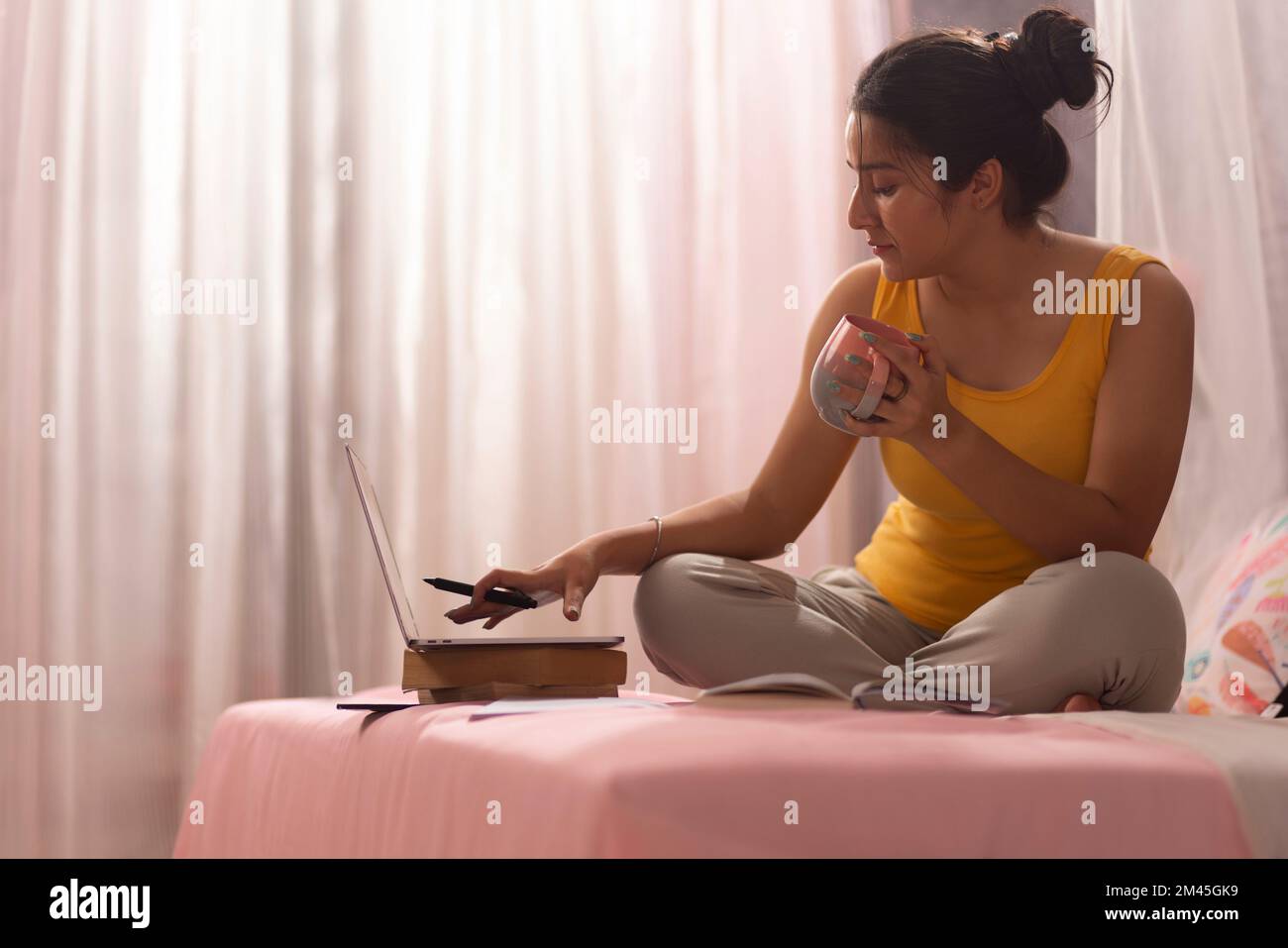 Ragazza adolescente bere caffè durante lo studio in camera da letto Foto Stock