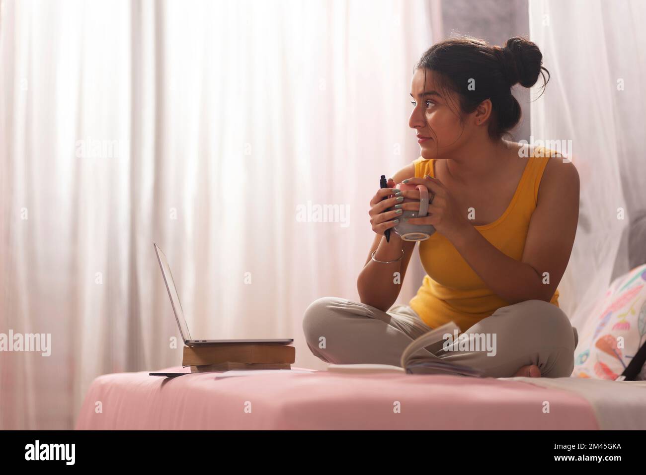 Ragazza adolescente bere caffè durante lo studio in camera da letto Foto Stock