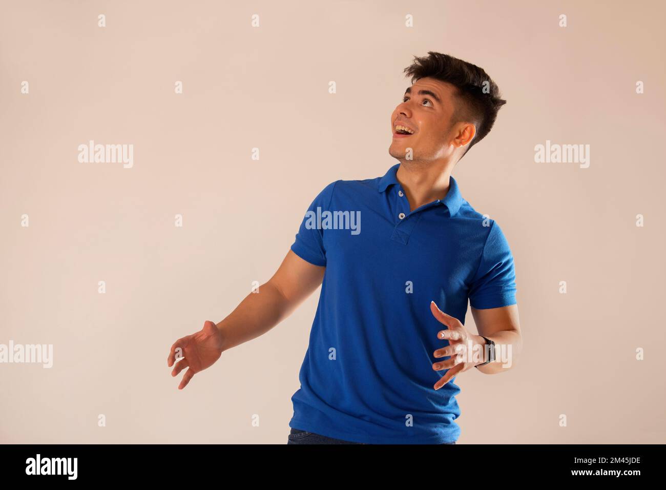 Giovane uomo in t-shirt blu che guarda sopra su sfondo bianco Foto Stock