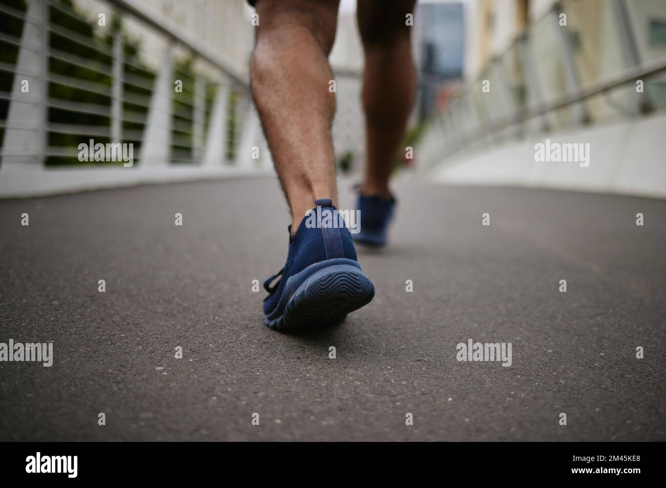 Fitness, gambe o runner camminando su un ponte di città in un caldo per l'allenamento, l'esercizio cardio o l'allenamento muscolare del vitello. Benessere, zoom o sport atleta Foto Stock