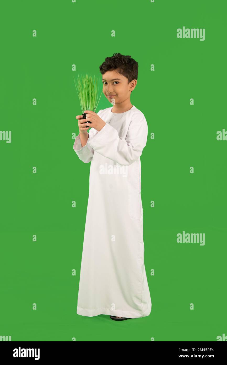 Emirati ragazzo che tiene in vaso pianta. Foto Stock