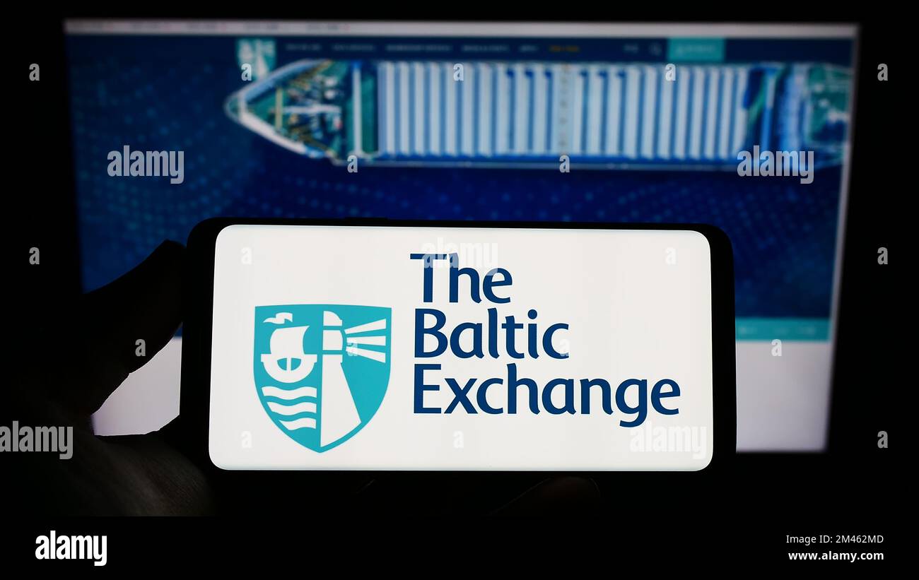 Persona che detiene uno smartphone con il logo della società britannica The Baltic Exchange Limited sullo schermo di fronte al sito Web. Messa a fuoco sul display del telefono. Foto Stock