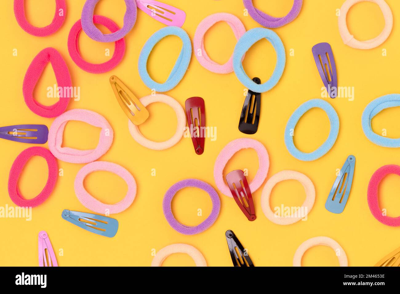 Molti piccoli crunchies multicolori dei capelli e clip su uno sfondo giallo. Foto Stock