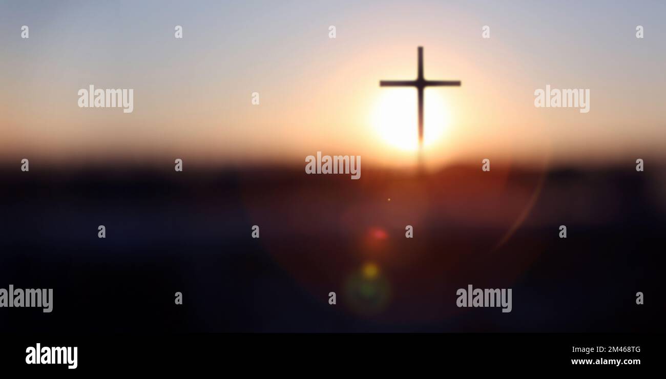 Splendente sfondo all'alba del nuovo anno con il luminoso bokeh del sole che sorge e la silhouette della Santa croce di Gesù Cristo Foto Stock