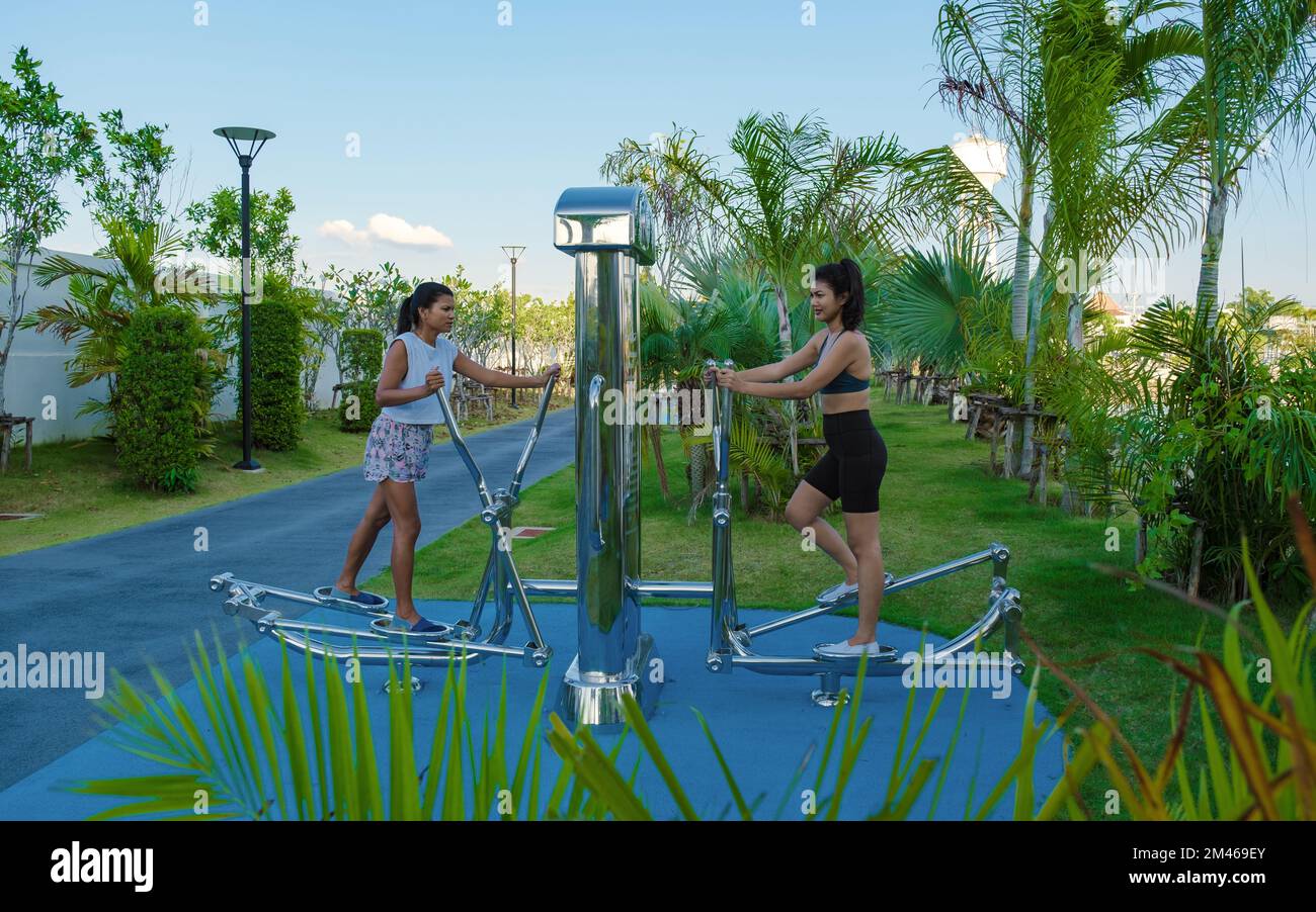 Due donne asiatiche allenarsi fitness in un parco pubblico a Pattaya Thailandia. Donna thailandese matura esercizio in un parco con palme in città Foto Stock