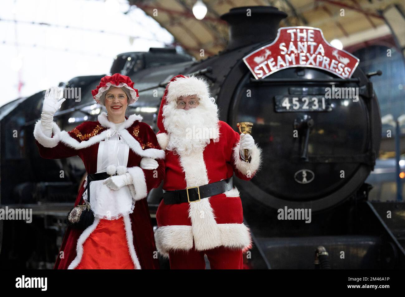 Le persone vestite come Babbo Natale e Mrs Claus alla Victoria Station di Londra, prima di salire a bordo del Babbo Natale Steam Express, con carrozze degli anni '70 decorate in modo originale, per un viaggio di 1 ora e 45 minuti a vapore intorno a Londra. Data immagine: Lunedì 19 dicembre 2022. Foto Stock