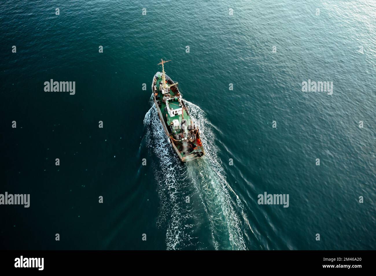 Barca da pesca cattura pesce vista dall'alto dal drone. Piccola nave da pesca a strascico sulla superficie del mare. Foto Stock