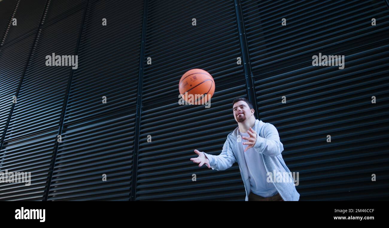 Giovane uomo con giù sindromi buttare via palla di basket. Foto Stock