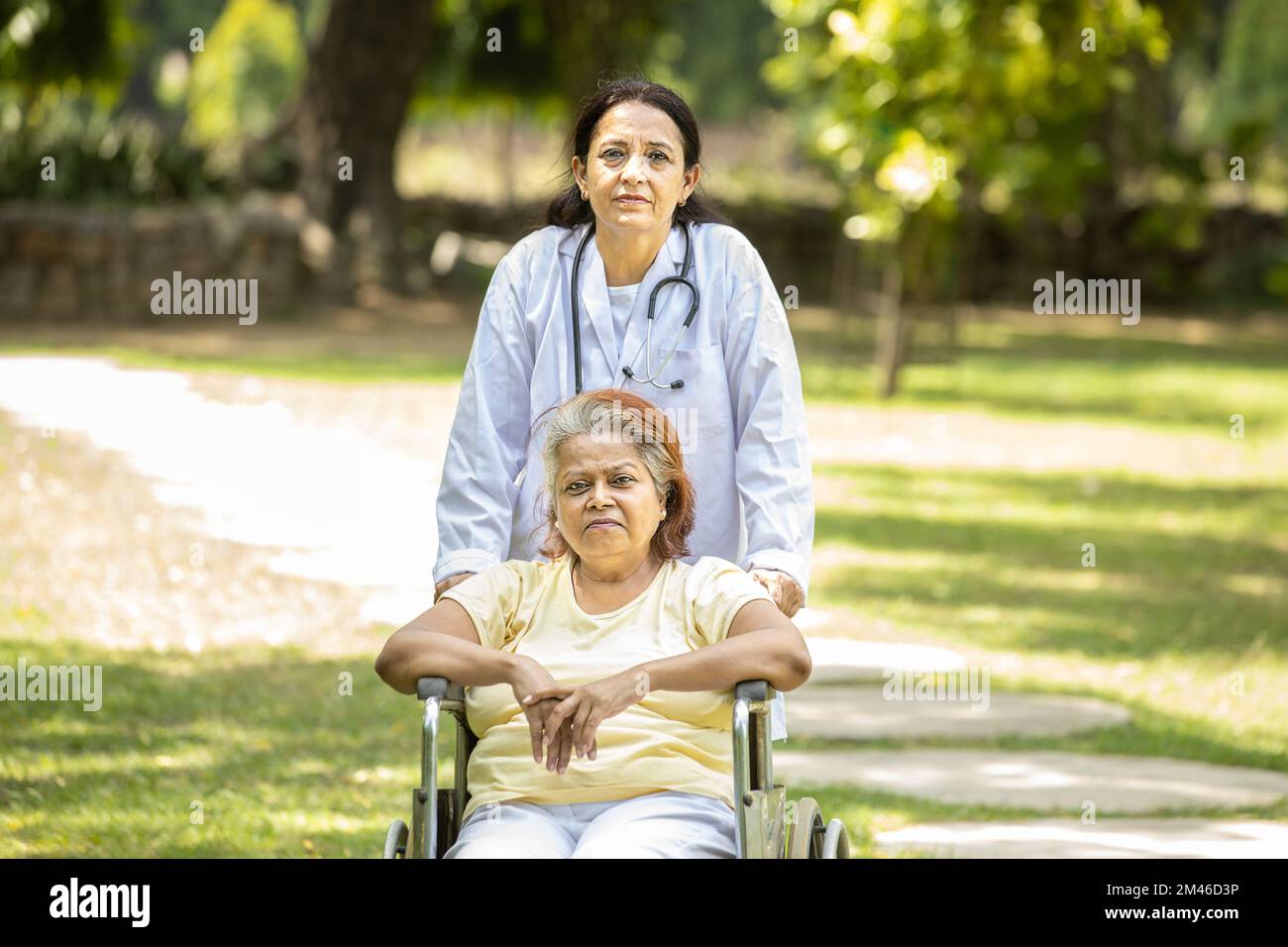 Infermiera indiana che si prende cura di una paziente anziana in sedia a rotelle all'aperto nel parco, medico asiatico aiutare e sostenere anziani anziani anziani anziani Foto Stock