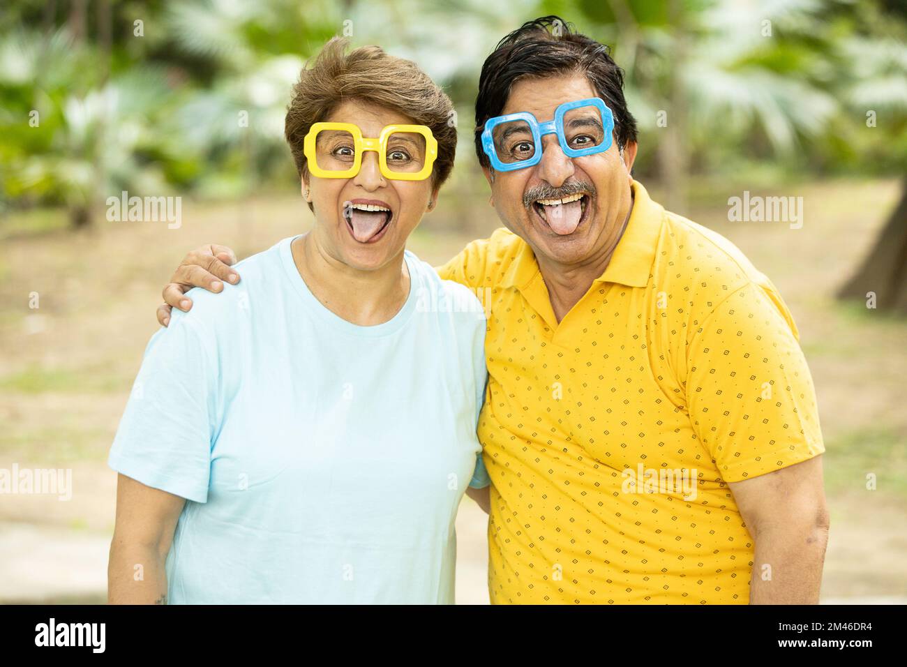 Ritratto di pazzo eccitato divertente coppia indiana anziana indossando gli occhiali funky all'aperto al parco. Persone mature che fanno i volti. Foto Stock