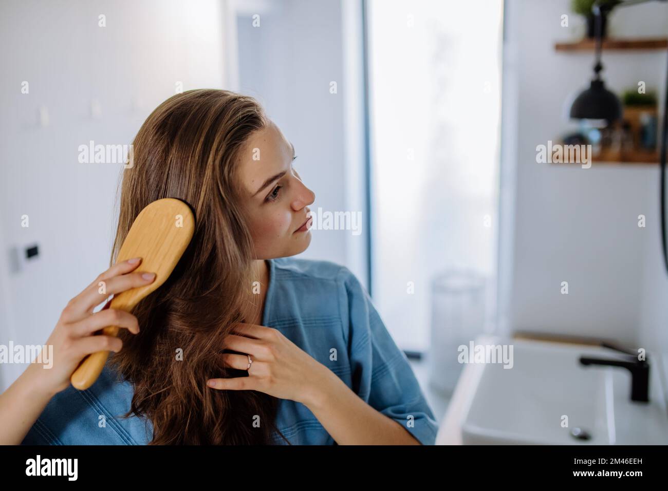 Giovane donna che si prende cura dei suoi capelli, mattina bellezza routine concetto. Foto Stock