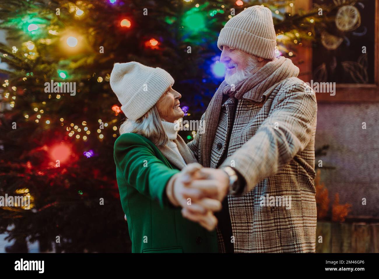 Coppia anziana che ha un momento romantico al mercato di natale all'aperto, ballando vicino albero di natale. Foto Stock