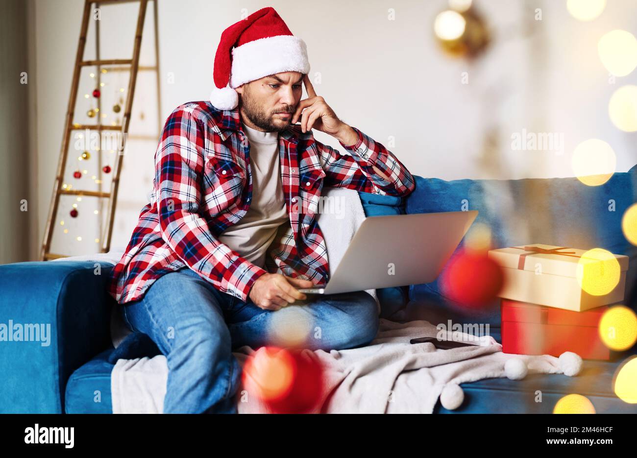 Uomo da solo a Santa Hat seduto a casa e al lavoro sul notebook durante le  vacanze di Natale Foto stock - Alamy