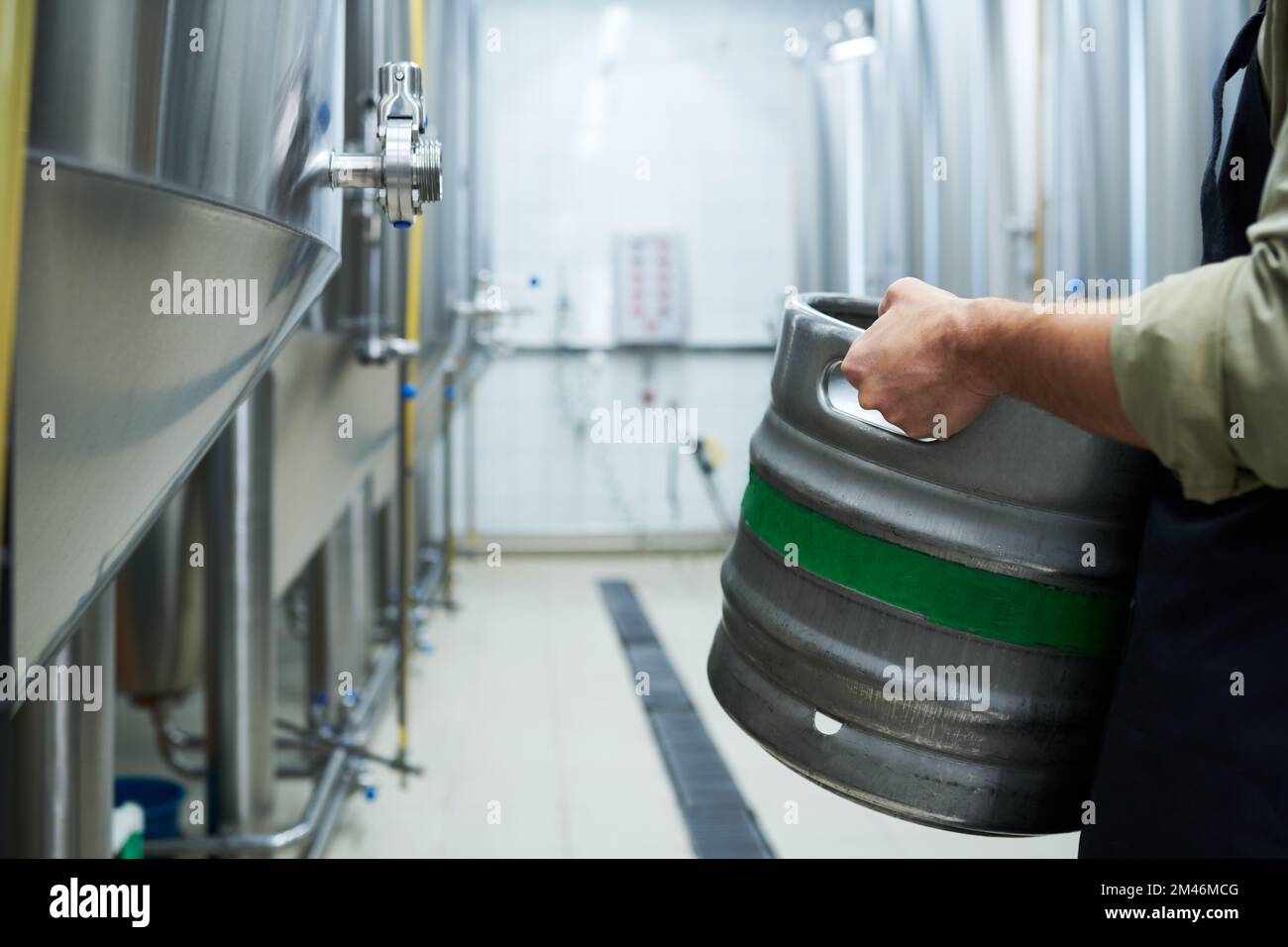 Immagine ritagliata del produttore maschio che trasporta il barile con birra fresca Foto Stock