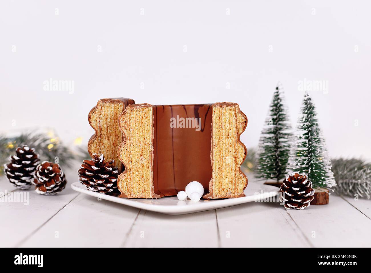 Tagliate la tradizionale torta invernale tedesca a strati chiamata 'Baumkuchen' glassata con cioccolato di fronte alla decorazione stagionale Foto Stock