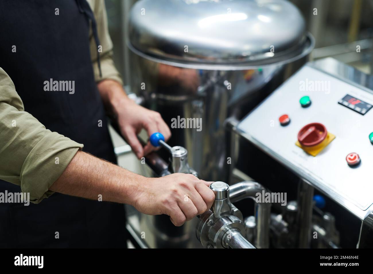 Mani del lavoratore che utilizza l'attrezzatura della birreria per impostare la pressione necessaria Foto Stock