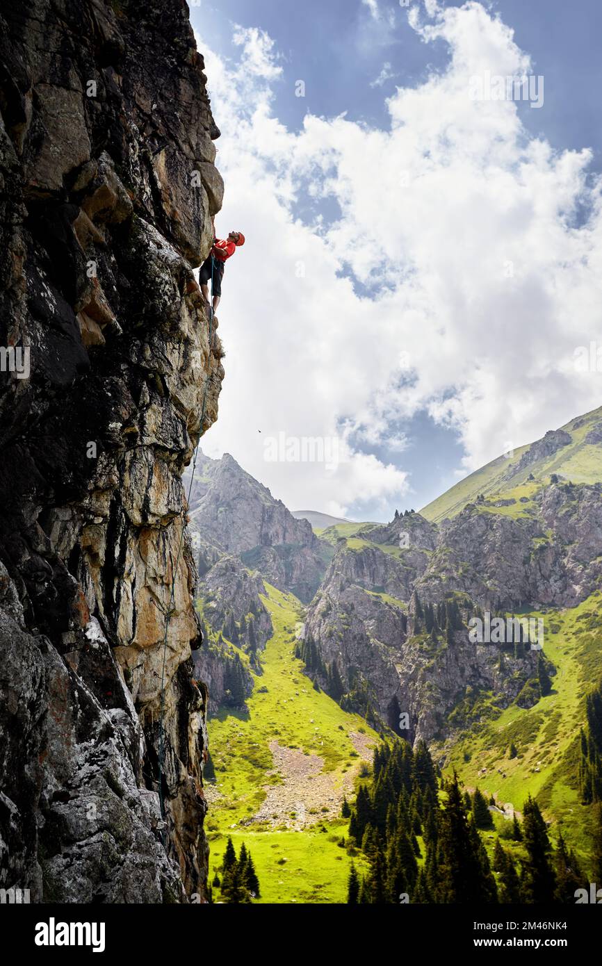 Adatta un atleta forte nella silhouette rock climbing sulla parete verticale alta sulle montagne Tyan Shan in Kazakistan Foto Stock