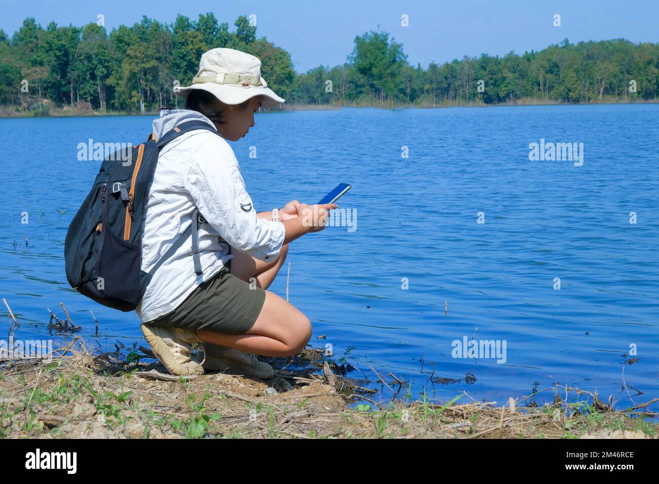 Donna ambientalista che utilizza il telefono cellulare per registrare l'analisi degli agenti patogeni nelle acque naturali. Concetto di acqua ed ecologia Foto Stock