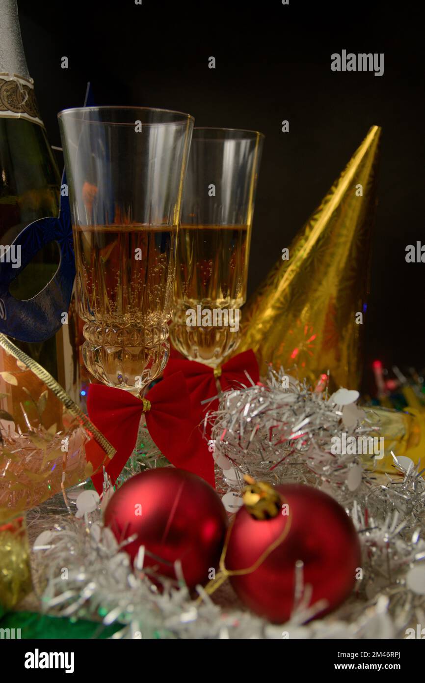 Due bicchieri di champagne su un tavolo decorato con oggetti di festa come cappelli e maschere dai colori vivaci e tinsel, per celebrare la fine dell'anno Foto Stock Due bicchieri di champagne su un tavolo decorato con oggetti di festa come cappelli e maschere dai colori vivaci e tinsel, per celebrare la fine dell'anno Foto Stock