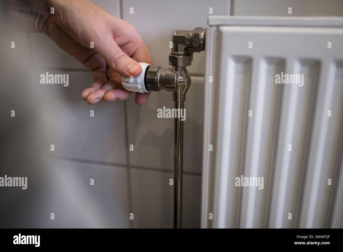 Persona che accende il termostato sul radiatore Foto Stock