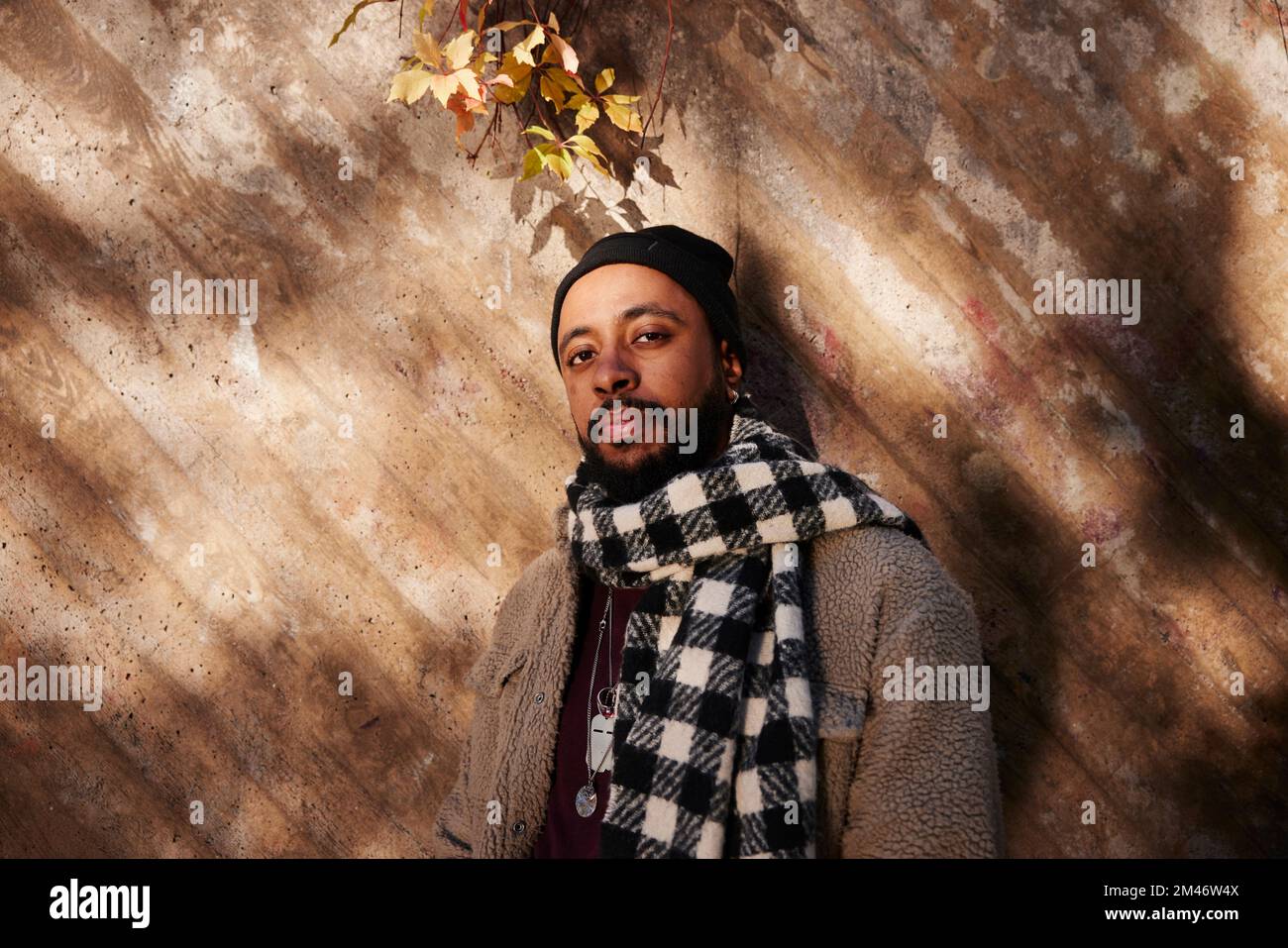 Uomo contro parete che guarda la telecamera Foto Stock