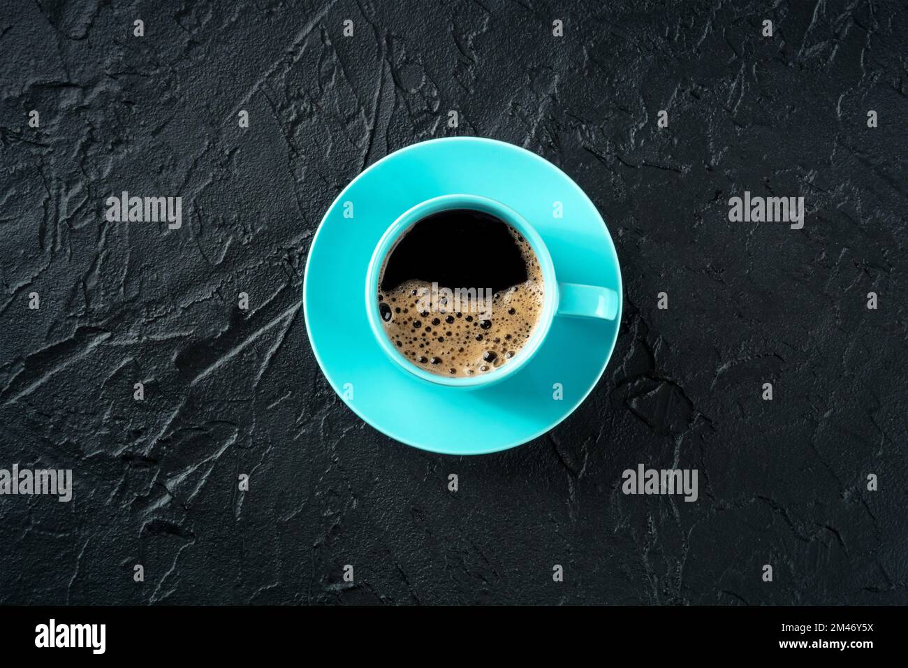 Tazza da caffè, getto piatto sopra la testa su uno sfondo nero ardesia con un posto per il testo, bevanda espresso in una tazza blu vibrante Foto Stock