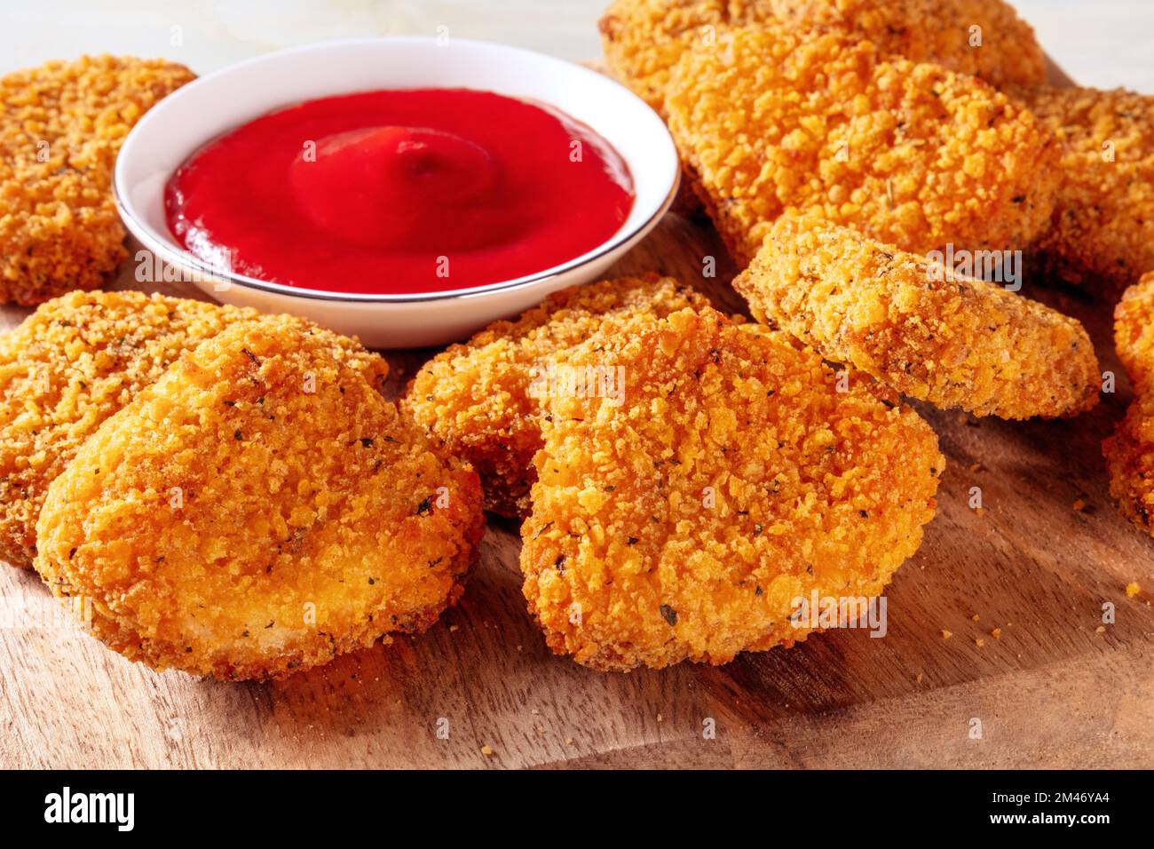 Pepite di pollo con ketchup primo piano su un asse di legno. Un gustoso spuntino con una salsa piccante Foto Stock