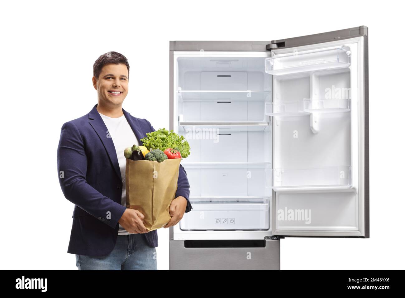 Giovane uomo con una borsa della spesa e un frigorifero aperto isolato su sfondo bianco Foto Stock