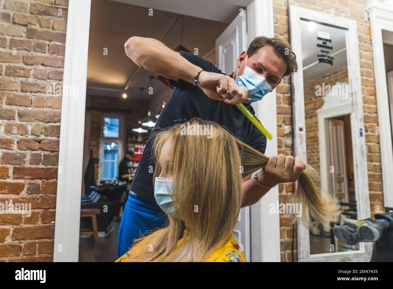 Acconciatura pandemica. Cliente e parrucchiere in maschere. Cliente felice che visita il salone del parrucchiere durante la pandemia. Protezione contro i virus. Foto di alta qualità Foto Stock