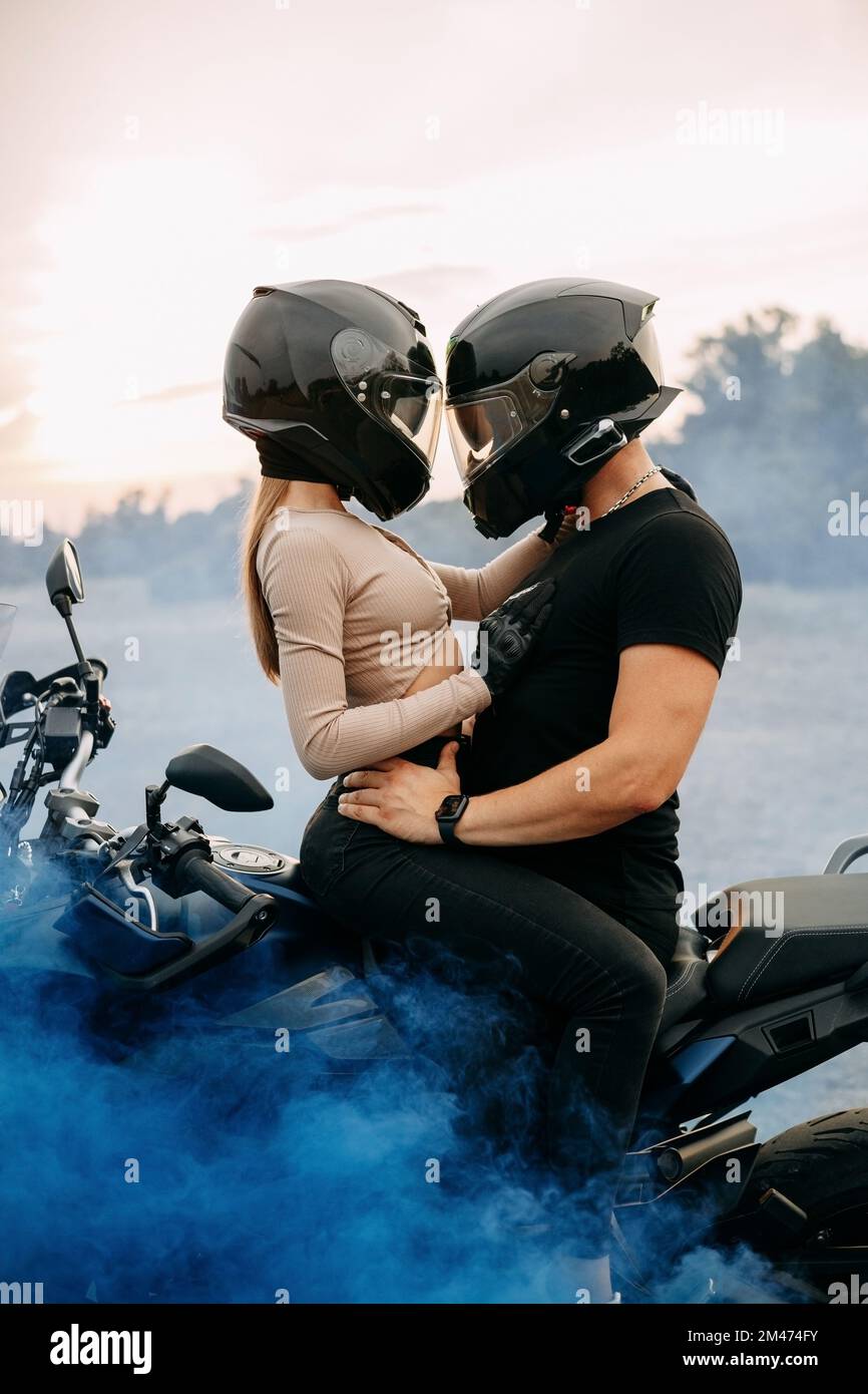 Uomo e donna in caschi moto vicino alla moto con fumo colorato