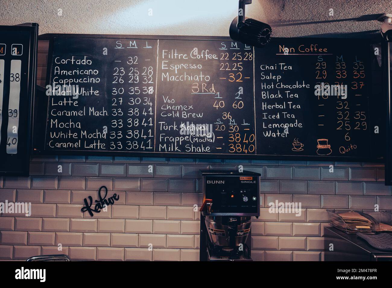 Menu del caffè sulla lavagna con prezzi e prodotti scritti a mano Foto Stock