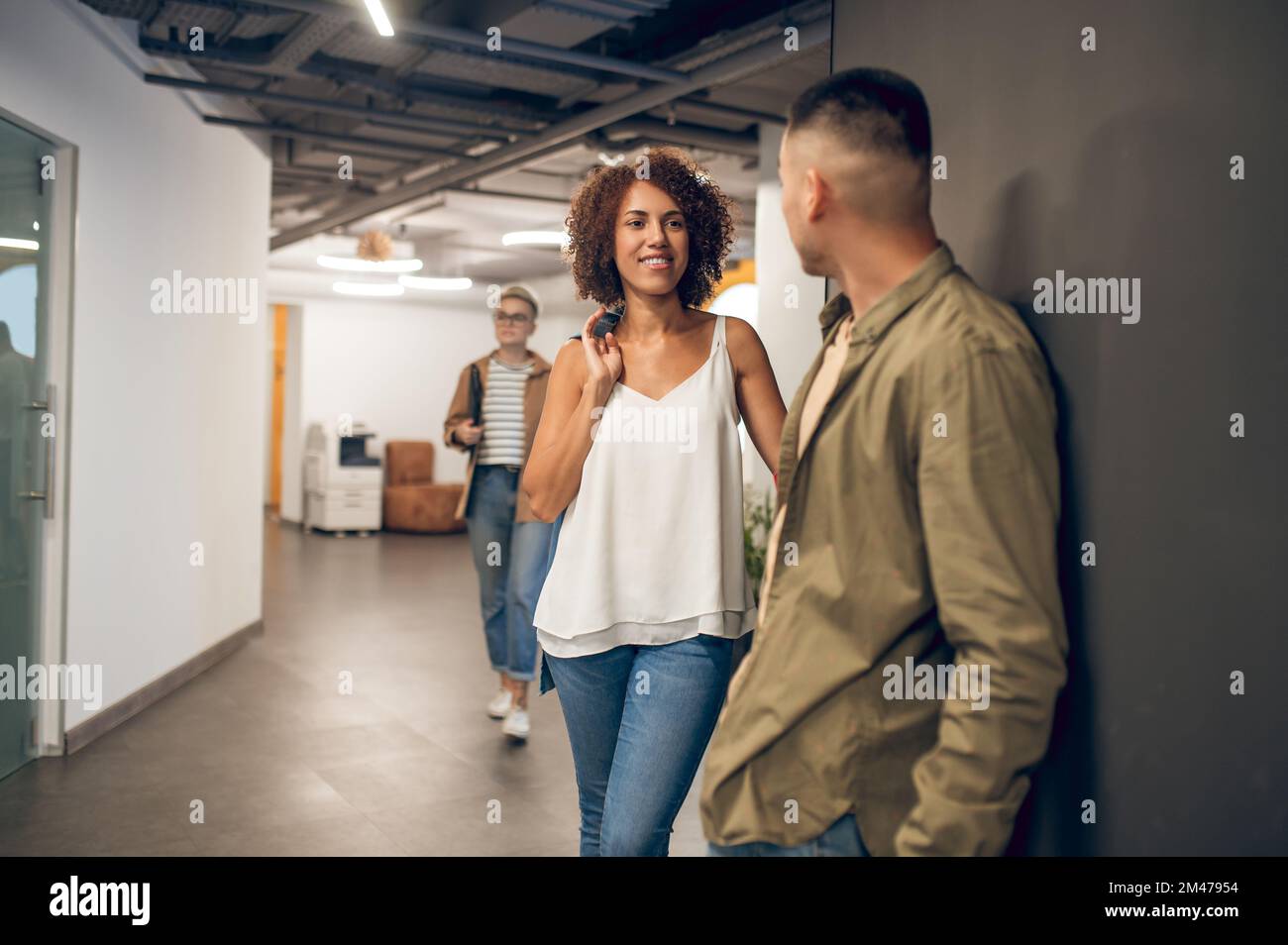 Il dipendente dell'azienda sorride alla sua collega nel corridoio Foto Stock