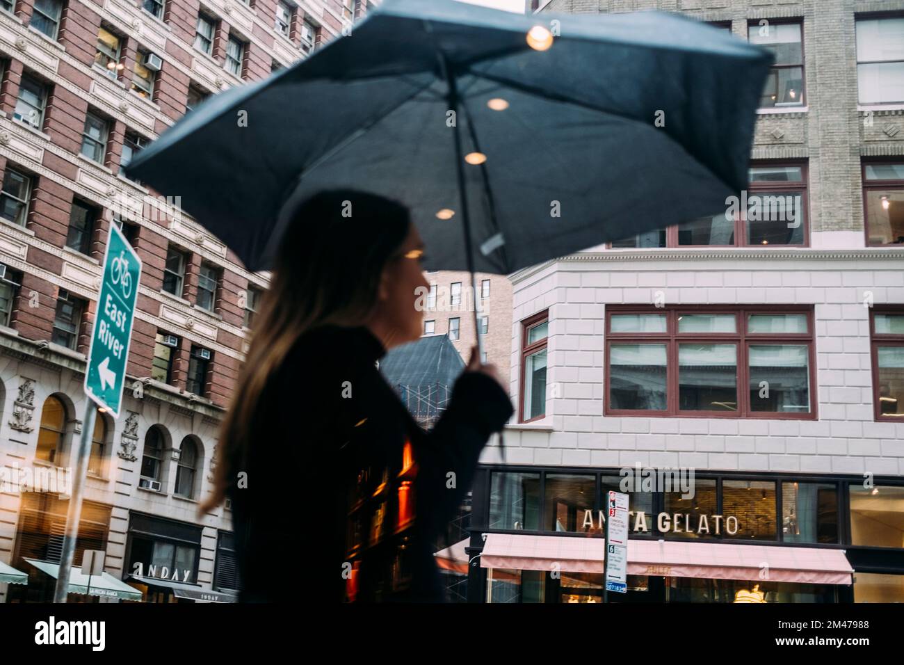 New York Manhattan, 02,10 - 10.10.22: Frau mit Regenschirm durch einer Fensterscheibe fotografiert. Foto: Presentazione Mika Volkmann Foto Stock