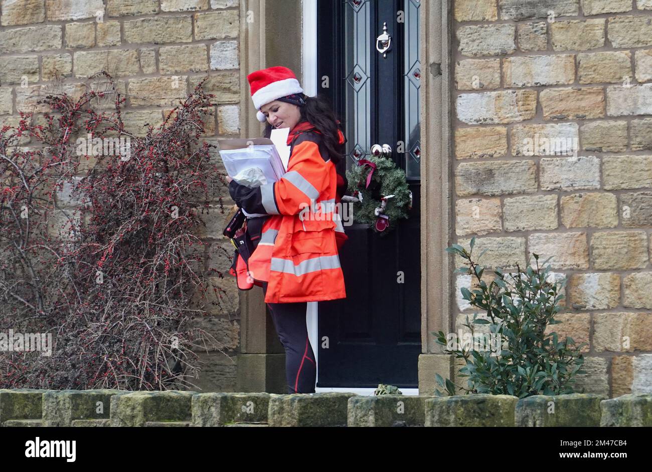 Una giovane ufficiale postale femminile in abito di Natale sul suo giro. Foto Stock