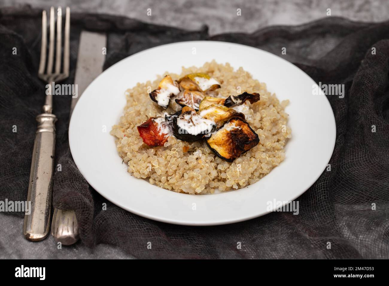 Quinoa cotta con verdure e salsa bianca su piatto bianco Foto Stock