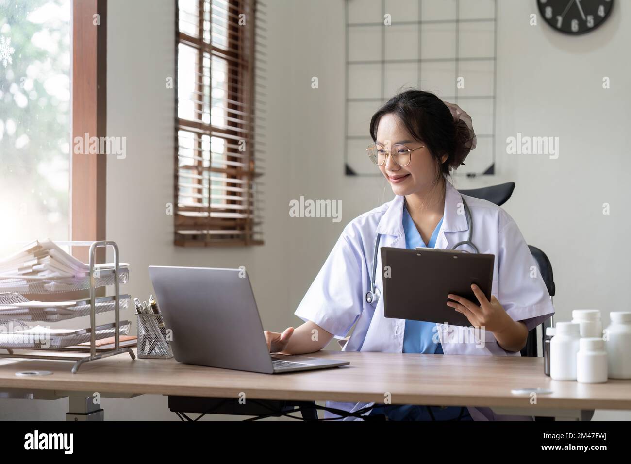 Medico asiatico che lavora con il portatile in ospedale e stetoscopio medico, la medicina sulla clipboard sul posto di lavoro. Foto Stock
