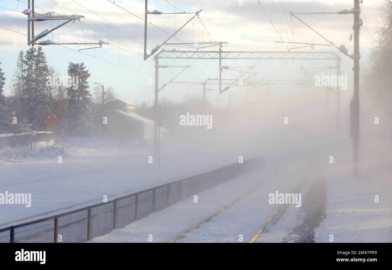 Un treno passava la piattaforma e lasciava polvere di neve nell'aria Foto Stock