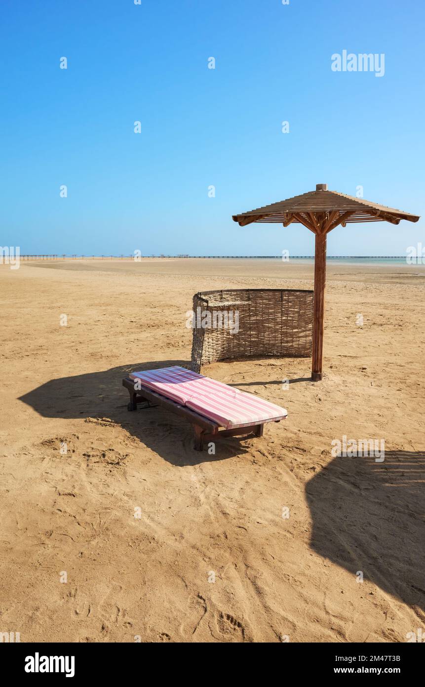Ombrellone e lettino in legno su una spiaggia tropicale. Foto Stock
