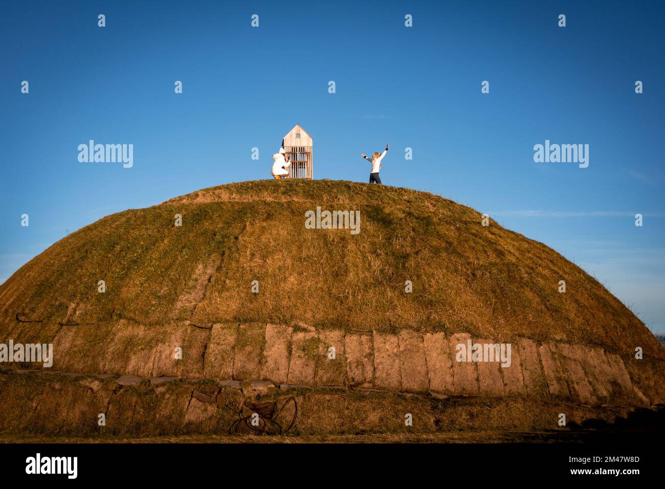 Reykjavik, Islanda - 25 novembre 2022: Thufa rotonda collina erbosa sulla costa oceanica di grandi. I turisti scattano foto in cima al tumulo. Foto Stock