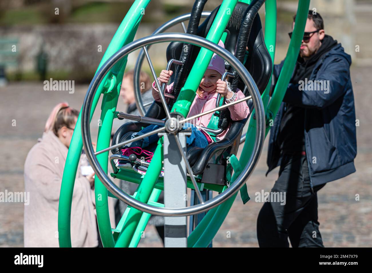 Dobele, Lettonia - 17 aprile 2022: I bambini godono l'attrazione estrema Aerotrim - un giroscopio umano con un sedile, chiamato anche un altalena 3D Foto Stock