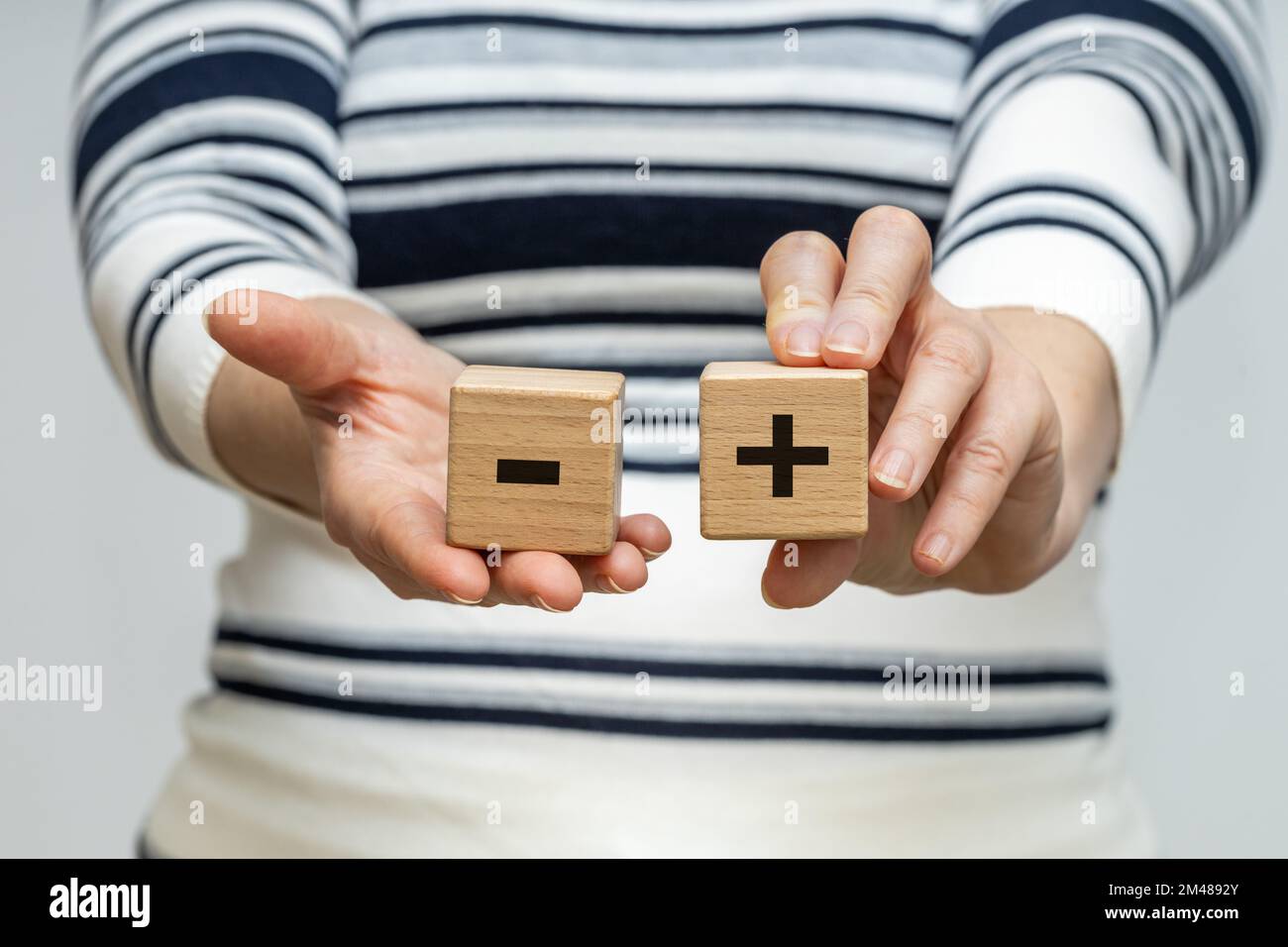 Pro e contro, Una donna tiene blocchi di legno con un simbolo positivo e negativo nelle sue mani, il concetto di pro e contro, su e giù Foto Stock