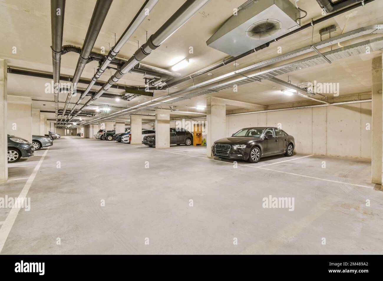 un parcheggio sotterraneo con auto parcheggiate nello spazio e nessuno a terra per vedere come sta andando Foto Stock