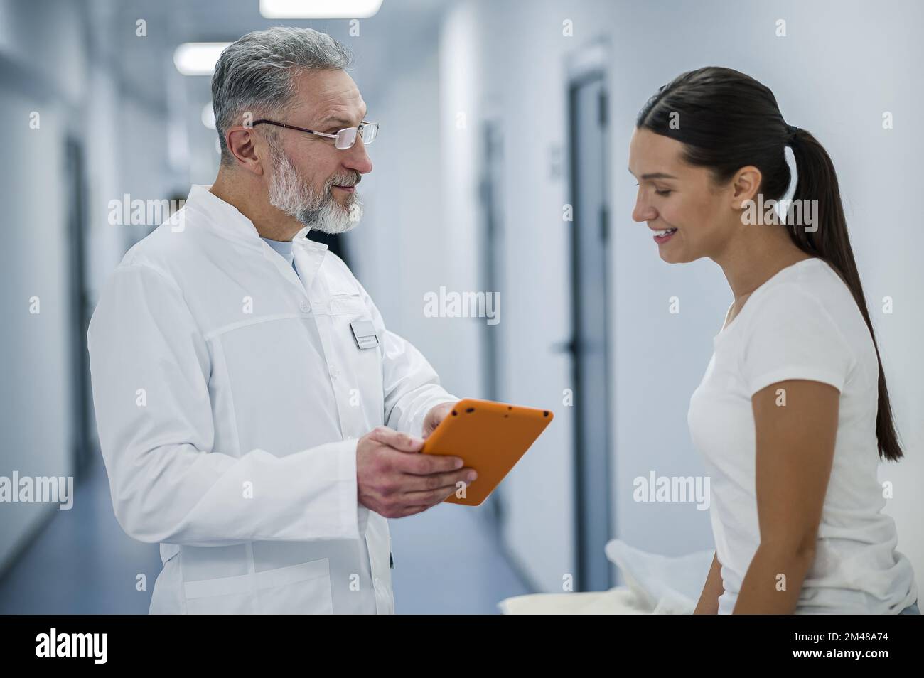 Medico dai capelli grigi che parla con il paziente prima della risonanza magnetica Foto Stock