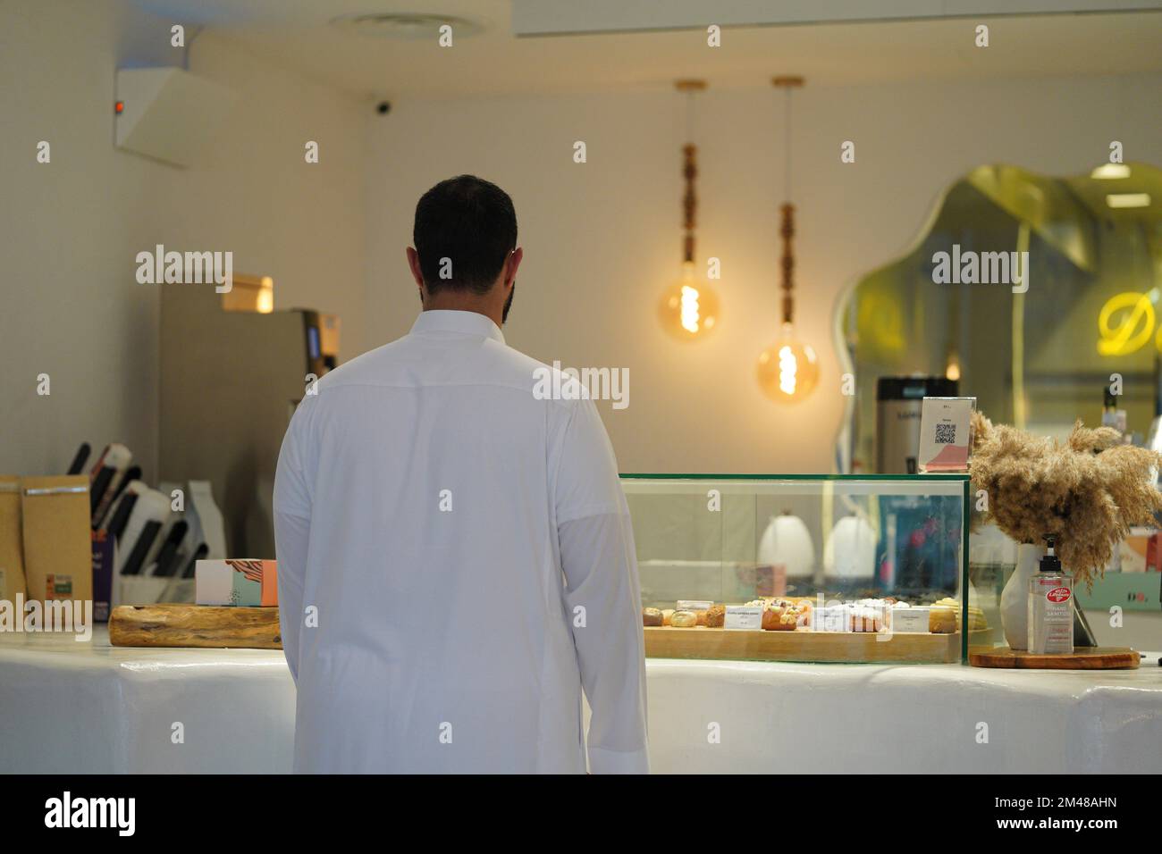 Uomo arabo che acquista caffè da una caffetteria. Dountughts e pasticceria caffetteria nel centro-est. Foto Stock