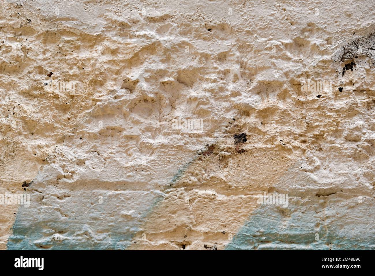 Muro di mattoni vecchio e danneggiato con imbiancatura e sfumature di vernice spray colla. Foto Stock
