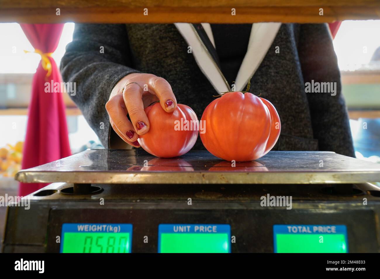 irriconoscibile venditore pesa alcuni pomodori sulla scala in un piccolo negozio Foto Stock